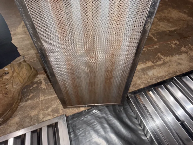 PMS technician holding a mesh filter partway through an on-site clean